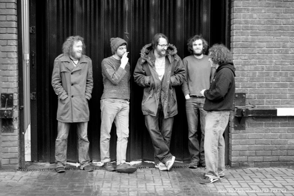 five men in their late twenties stood smoking and laughing